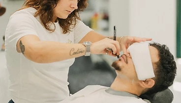 Cliente satisfeito a sorrir após corte finalizado pelo barbeiro