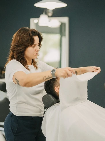 Barbeiro a cortar cabelo com camisolas de futebol emolduradas ao fundo