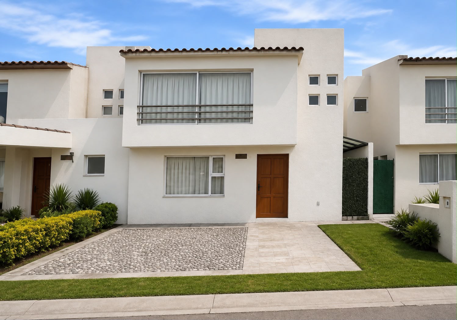 Fachada de residencia blanca de dos niveles con jardín frontal y techo de teja en proyecto entregado TEMBO