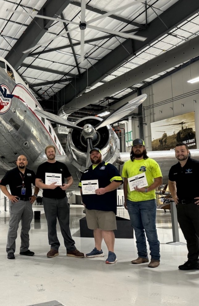 A&P Wash Services team posing with a polished vintage aircraft in a hangar