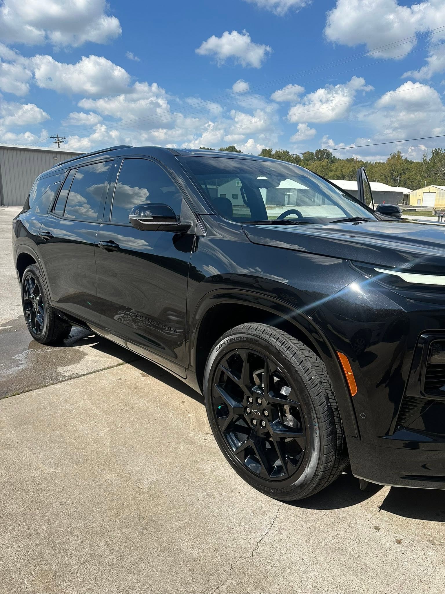 Glossy black Chevrolet SUV detailed to a mirror finish outdoors on a sunny day