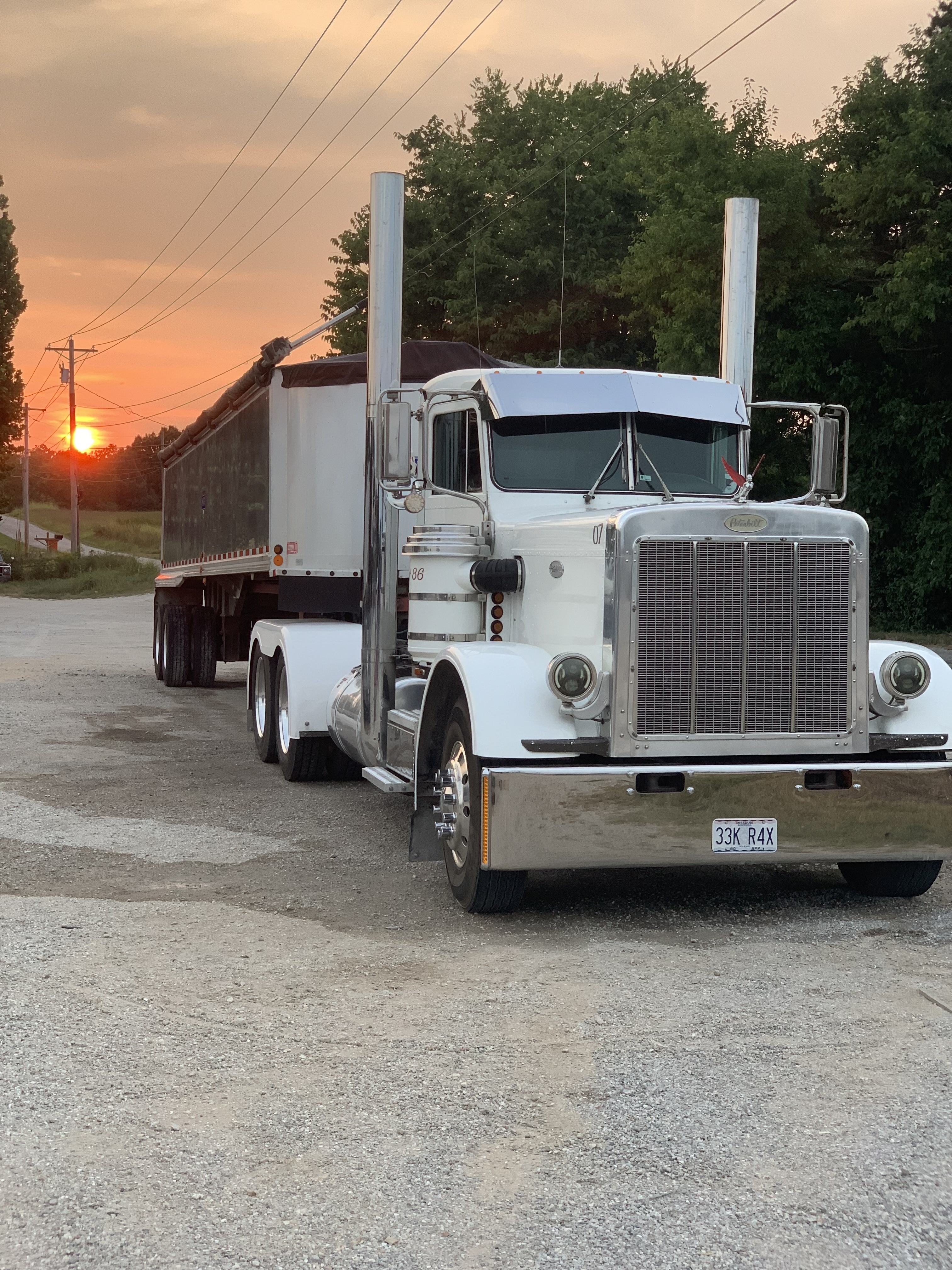 White Peterbilt semi-truck with a silver dump trailer parked at sunset after fleet washing by A&P Wash Services