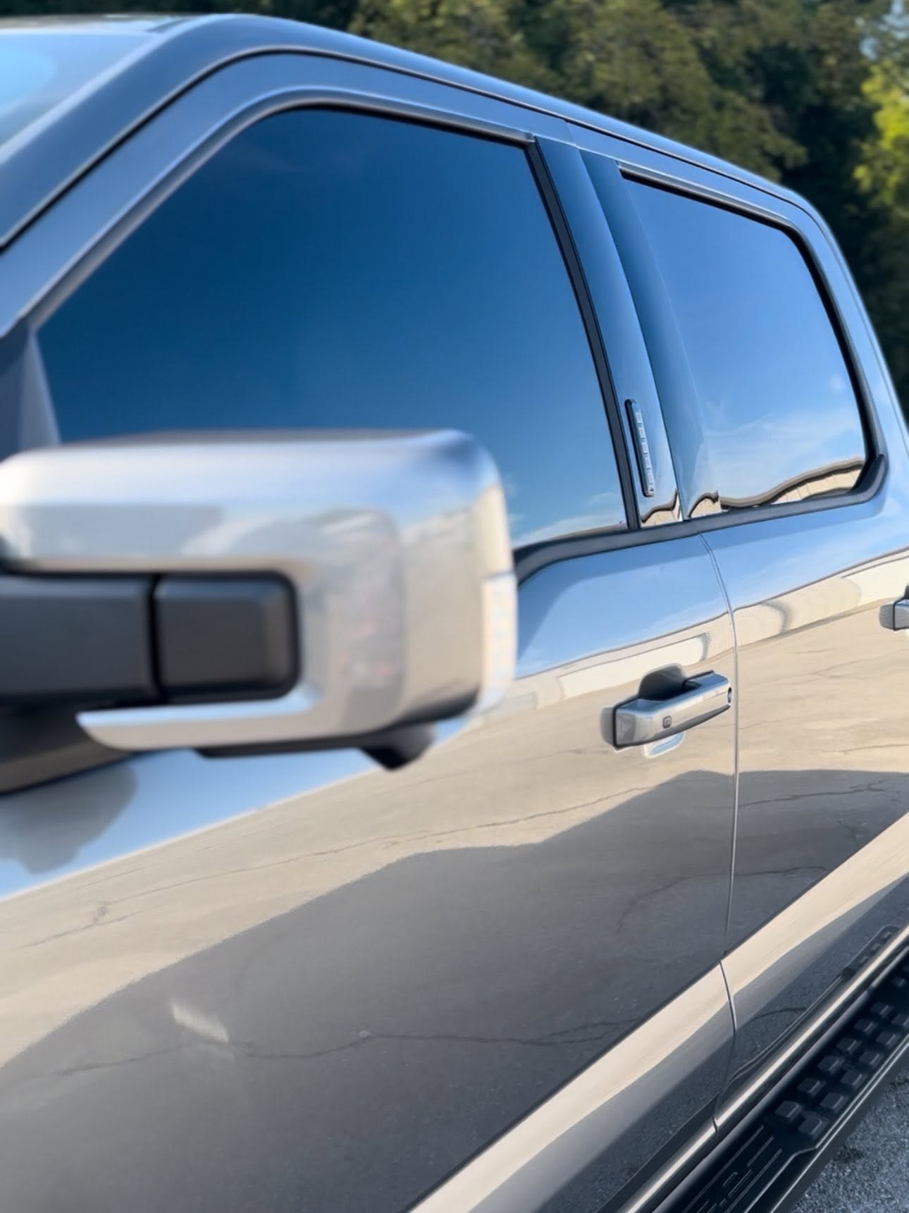 Mirror-like sky reflection on the hood of a ceramic-coated black Chevrolet SUV