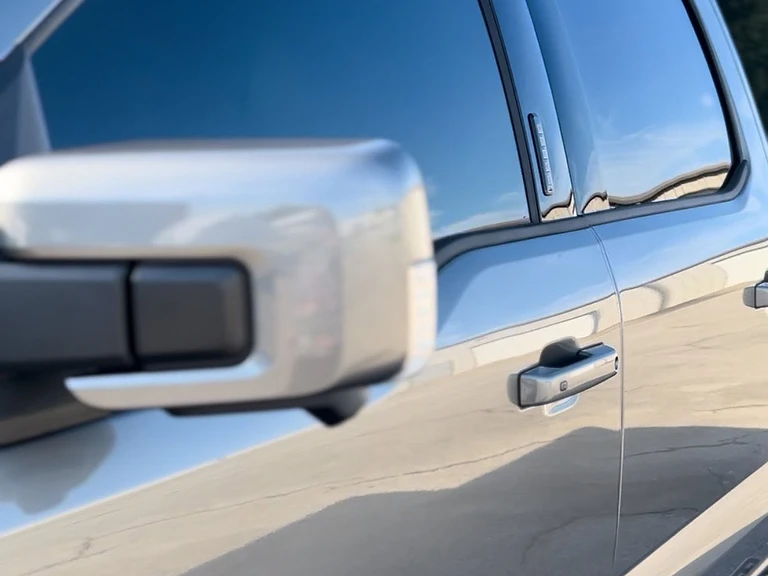 Silver 2025 Ford F-150 Lariat with a mirror-like ceramic-coated finish reflecting the sky and surroundings