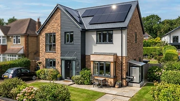 UK detached house with rooftop solar panels and an air source heat pump