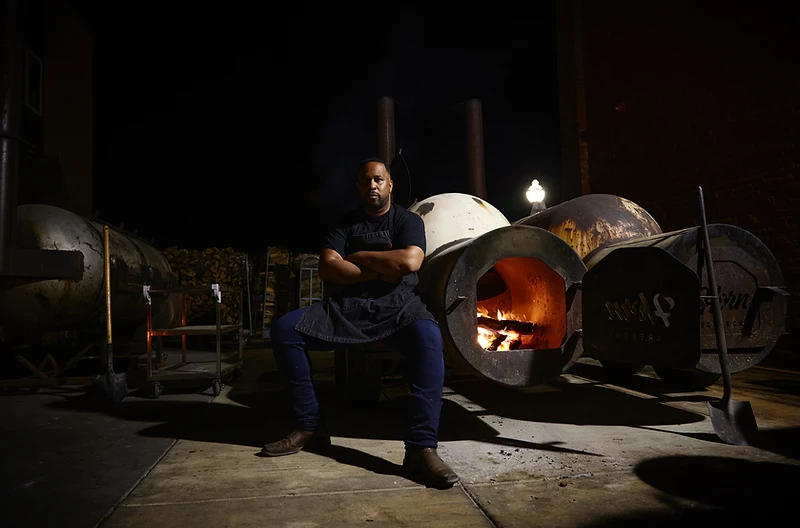 Chef Matt Horn at his smoker trailer at night, firebox glowing