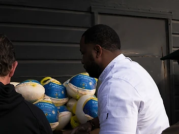 A chef and volunteers working beside stacks of frozen turkeys