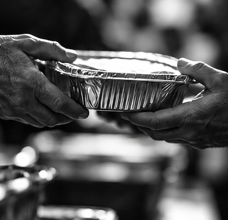 Hands exchanging a covered meal tray at a community distribution