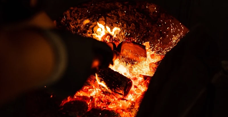 Pitmaster tending a glowing charcoal fire