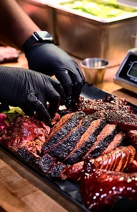 Hands plating smoked brisket and sausage