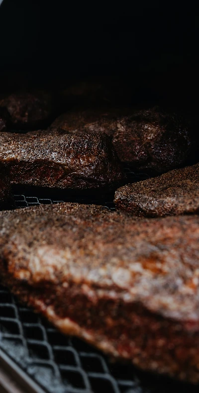 Briskets smoking in a live-fire pit
