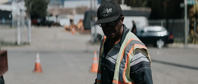 A member of the Horn Barbecue team in a safety vest holding stacked to-go meal containers