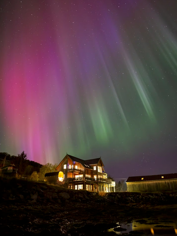 Northern lights over a wooden lodge on the Tromsø shoreline