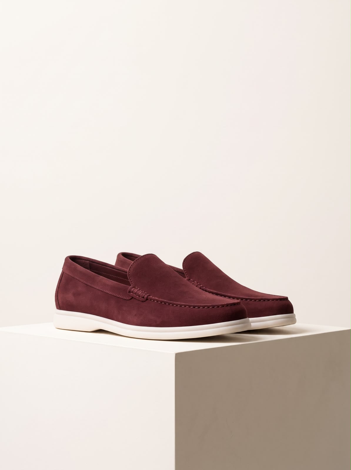 Burgundy suede loafers on plinth