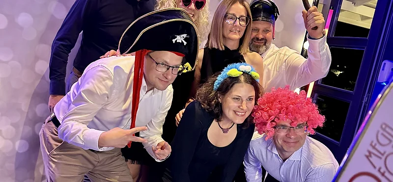Goście w rekwizytach pozujący przed tłem z ciepłych lampek przy fotolustrze MegaFota na rocznicy ślubu w Wisełce