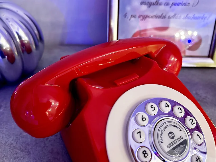 Czerwony telefon życzeń audio w stylu retro z tarczą i słuchawką obok instrukcji dla gości na przyjęciu weselnym | MegaFota Szczecin