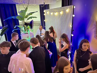 Stanowisko fotobudki klasycznej MegaFota z lampą błyskową, tłem w pasy i stołem pełnym rekwizytów na balu ósmych klas w Ricorii w Szczecinie