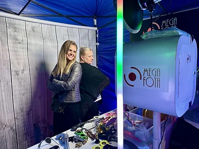 Dwie uczestniczki pozujące na tle z desek przy fotobudce klasycznej MegaFota podczas festynu miejskiego