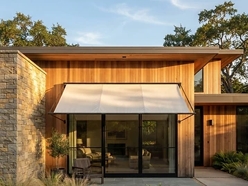 A residential window with a canvas awning providing shade in warm afternoon light