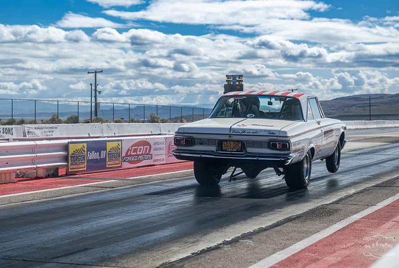 White drag racing pickup launching with its front wheels raised at Top Gun Dragstrip