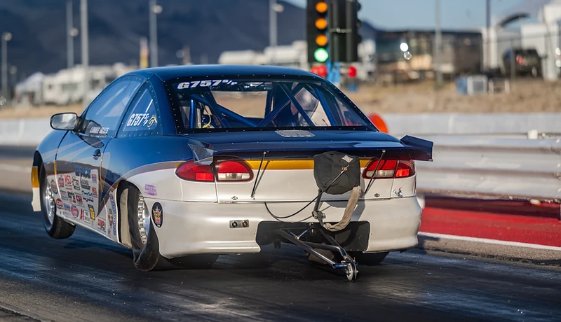 Black drag car producing tire smoke during a burnout at Top Gun Dragstrip