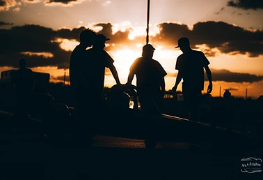 Race crew members silhouetted by sunset in the Top Gun Dragstrip pits