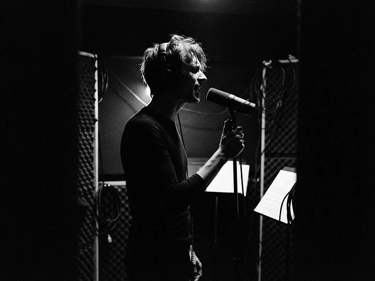 Vocalist silhouetted in a dark recording booth