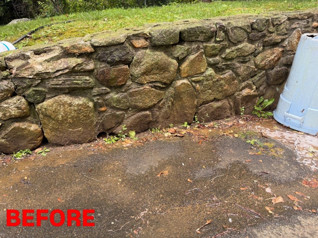 Stone retaining wall covered in moss, algae, and dirt before power washing