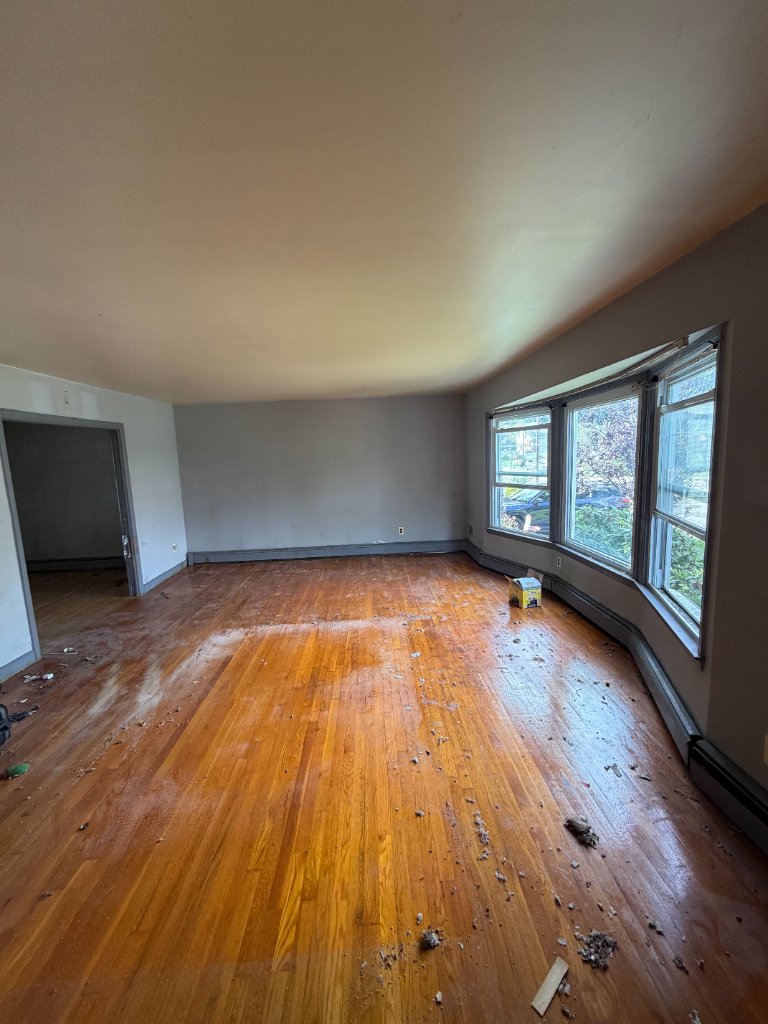 Same living room emptied to bare hardwood floors after furniture removal by Apex Property Services