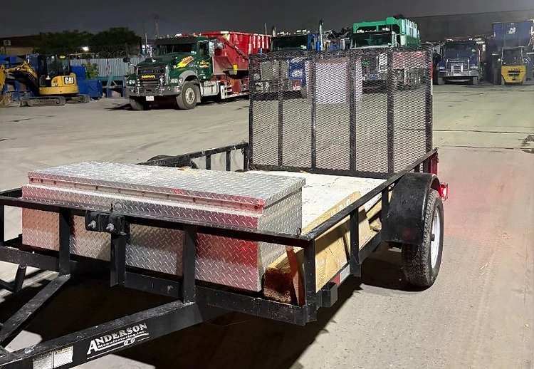 Apex Property Services loaded trailer at a transfer station at night, ready for a junk removal haul