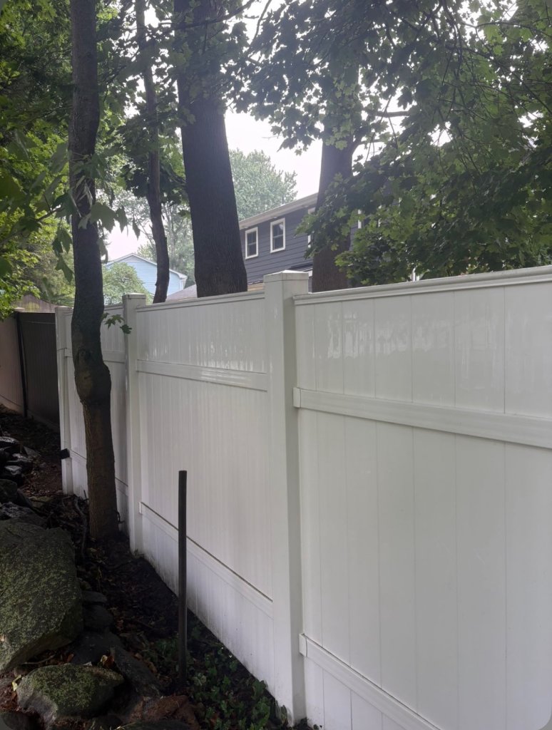 Same privacy fence line washed to a bright white finish after soft washing by Apex Property Services