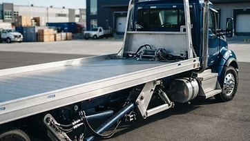 Empty flatbed tow truck arriving for a scheduled scrap car pickup