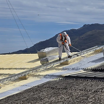 Spray foam being applied over an asbestos cement industrial roof