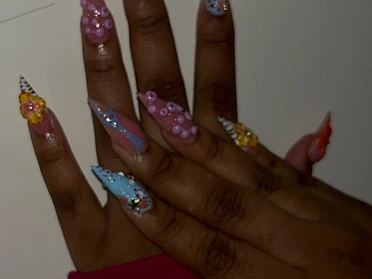 Long stiletto set with colorful 3D floral accents, pearl beads, and glitter detailing.