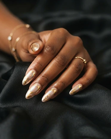 Elegant almond chrome nails with gold foil accents on a nude champagne base — mirror finish.