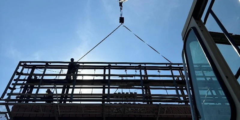 Cortes Contracting Services crane performing a heavy structural lift with crew on the structure