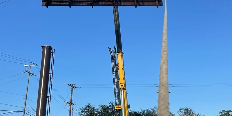 Cortes Contracting Services crane lifting a steel billboard frame into final position