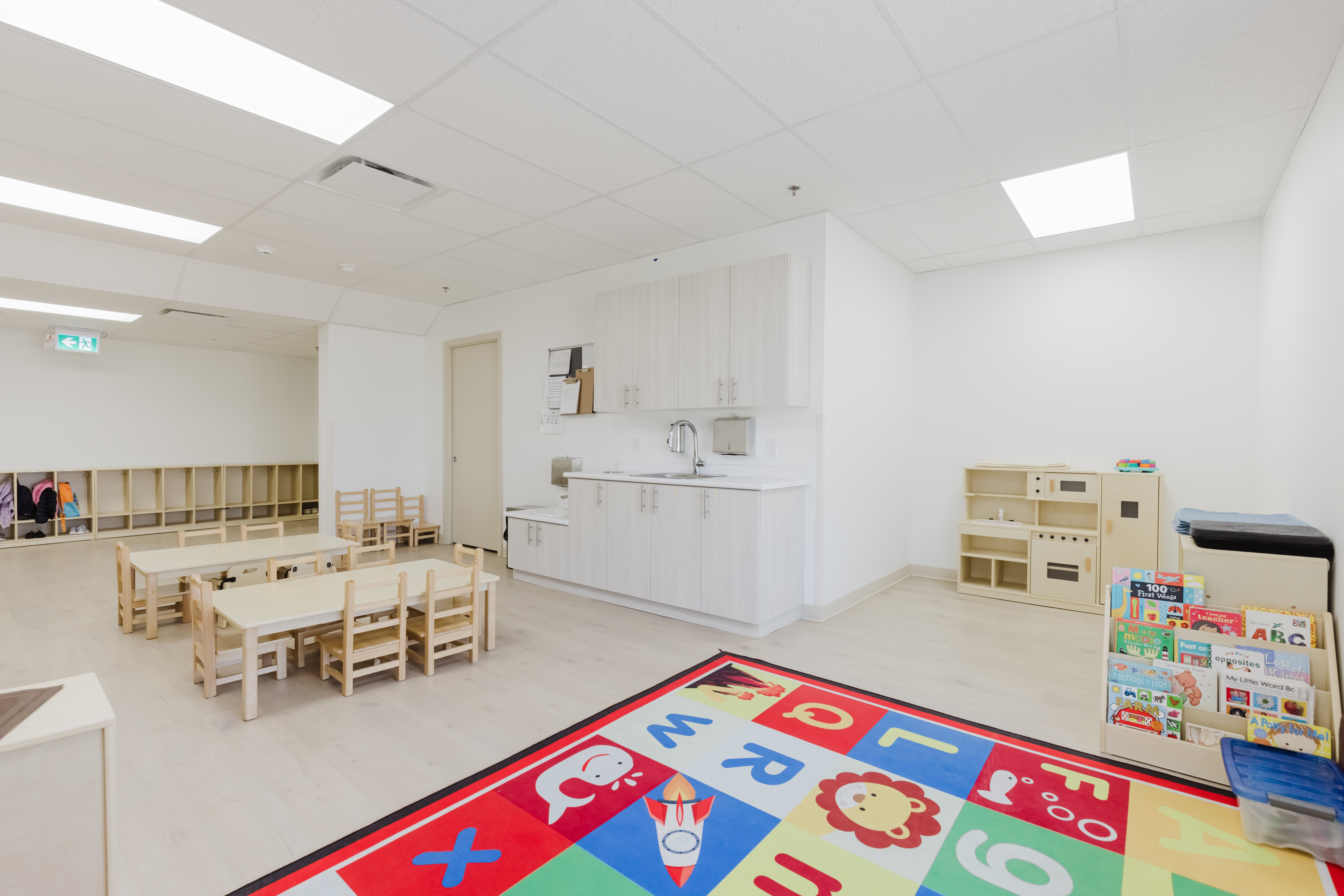 Bright toddler classroom with alphabet rug and learning materials at Kidzville