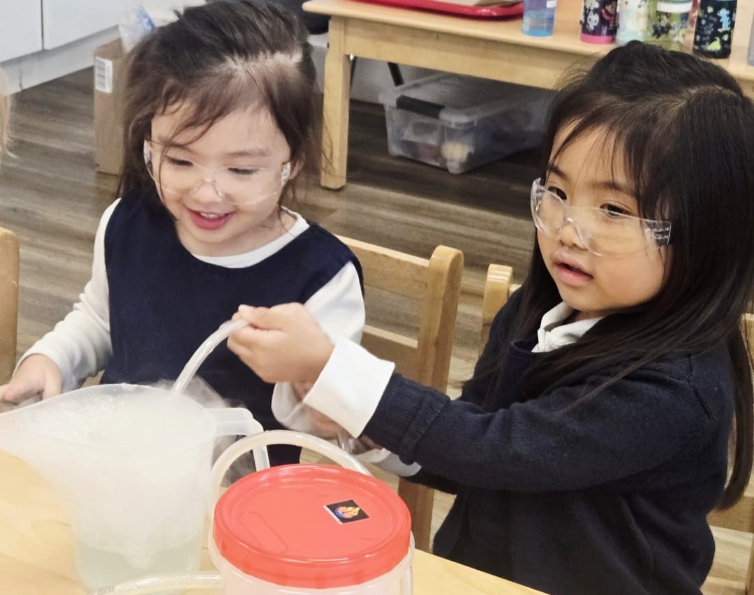Two children doing a science experiment with bubbles and safety goggles at Kidzville
