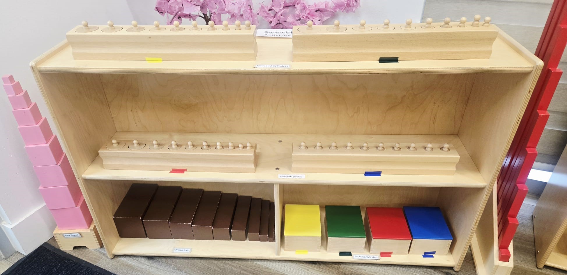 Montessori sensorial materials shelf with pink tower and brown stair at Kidzville
