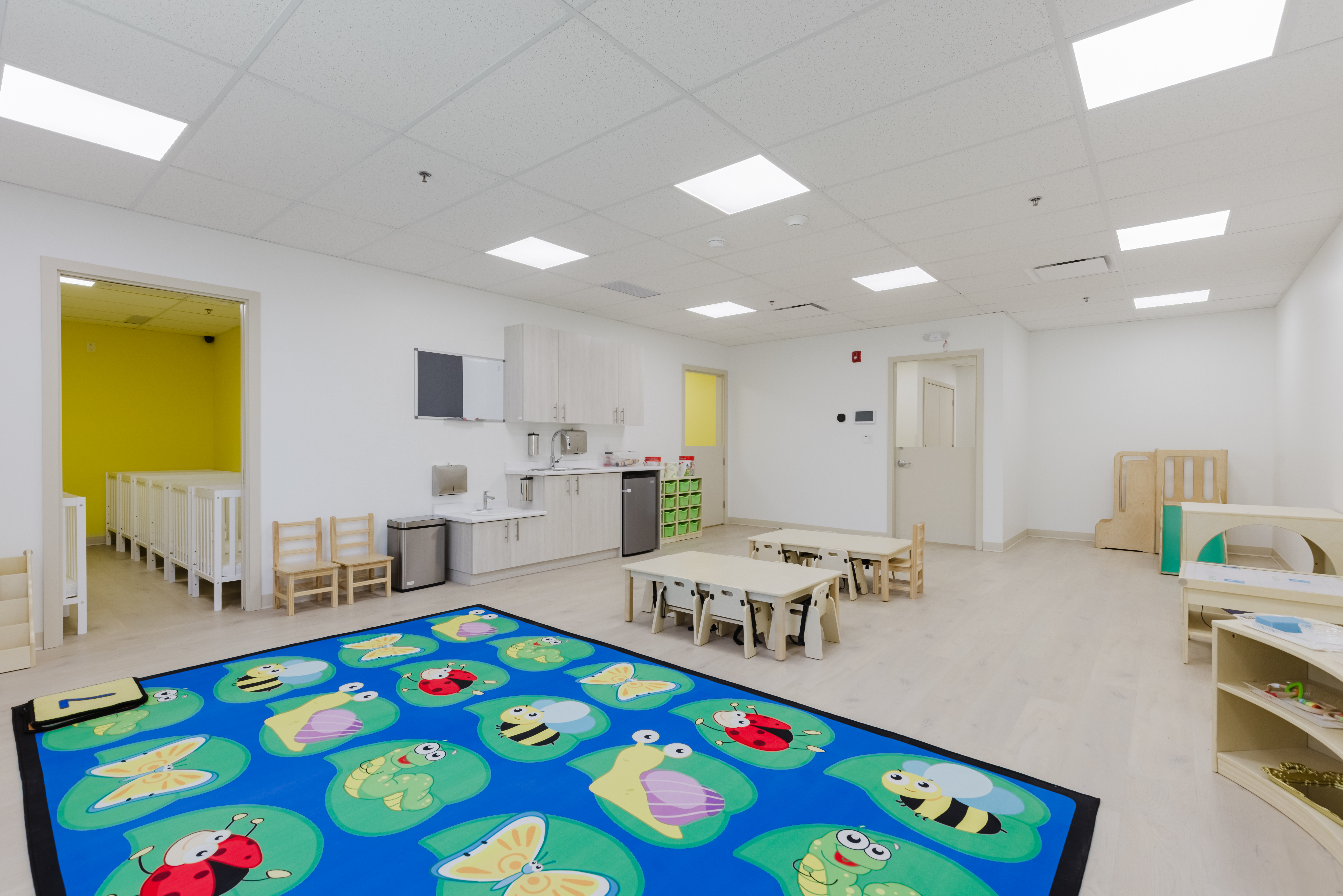 Infant room with outdoor garden access and busy board wall at Kidzville