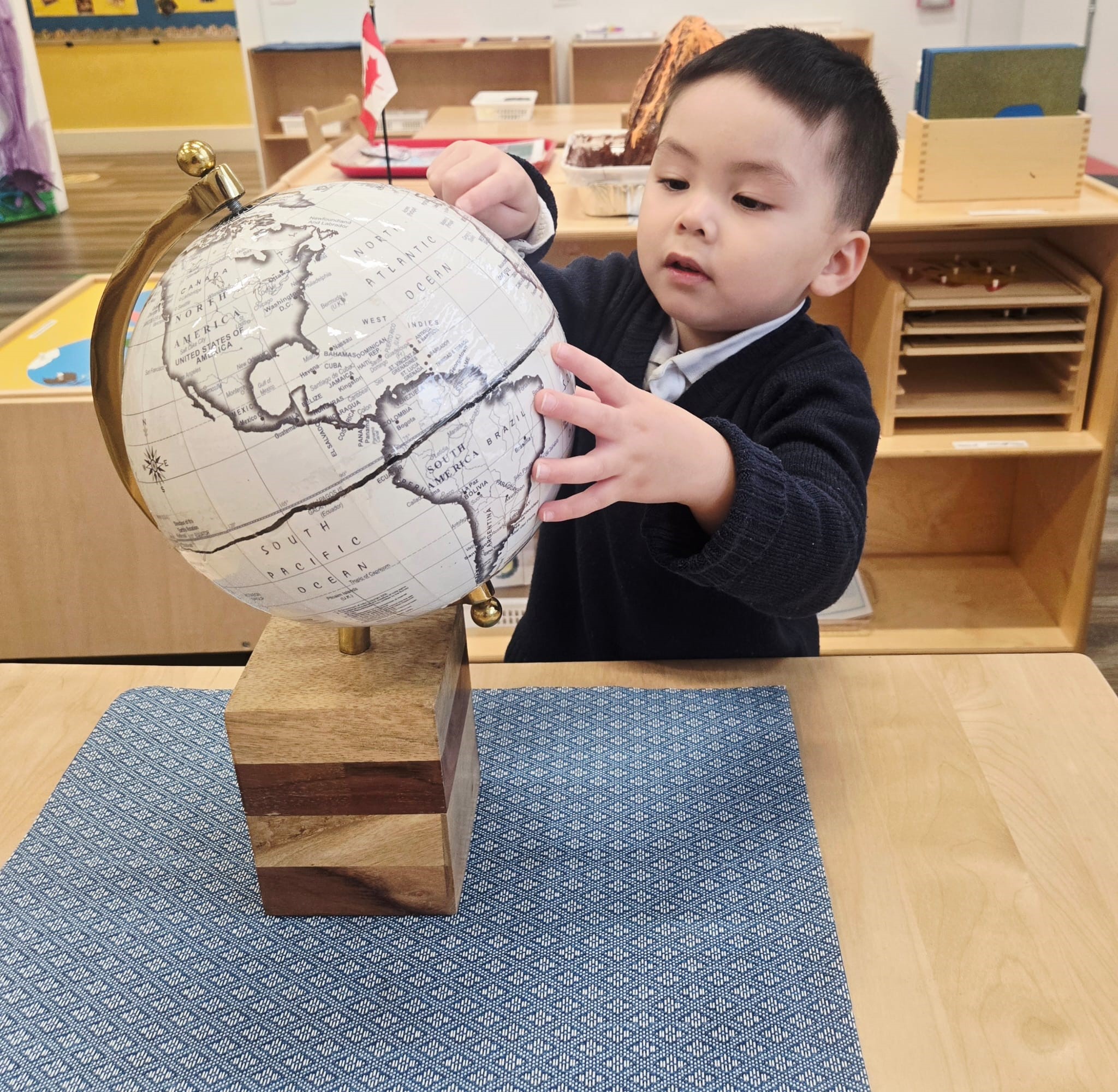 Young child exploring a globe in a Montessori classroom at Kidzville