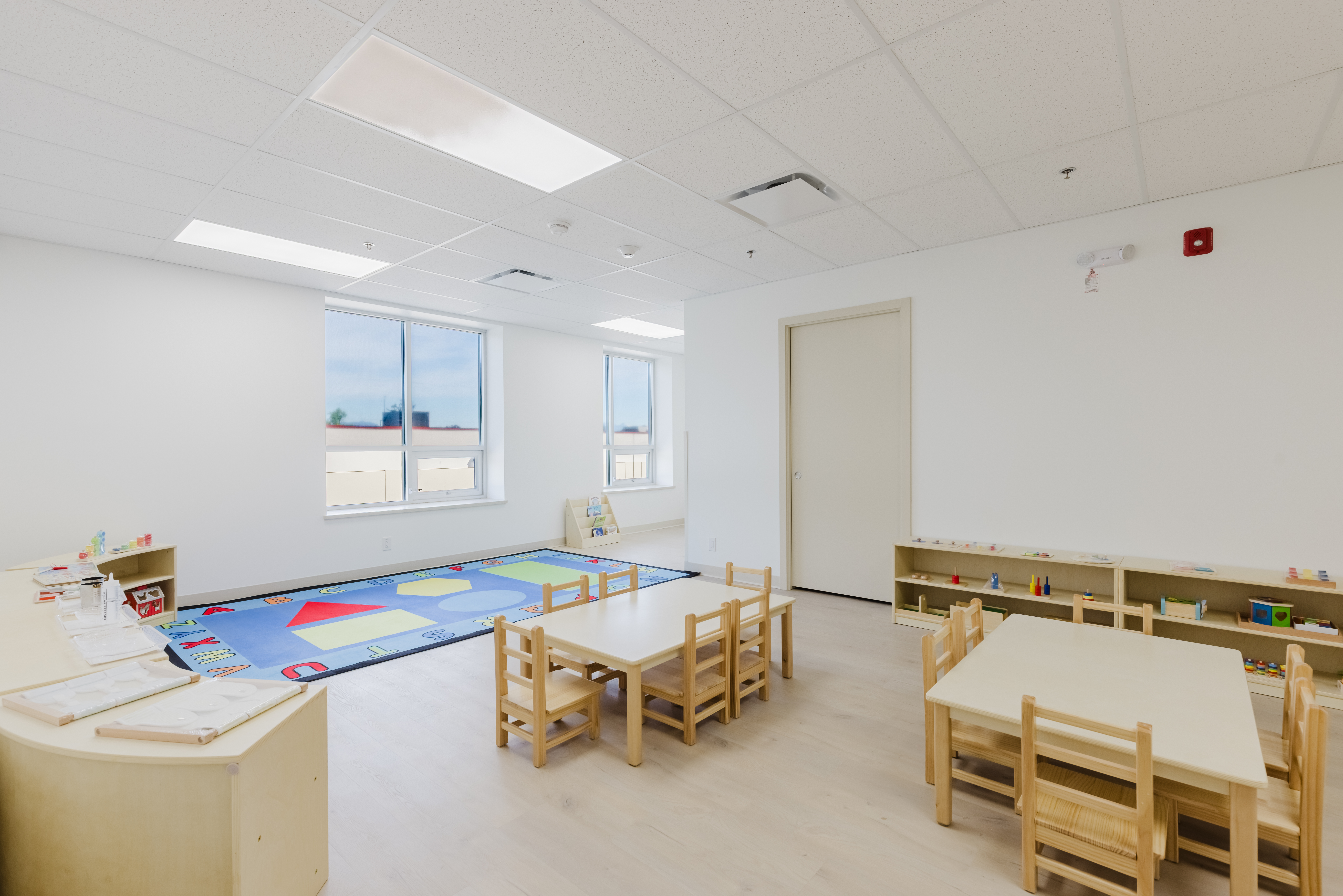 Spacious toddler room with Montessori shelves and children's tables at Kidzville