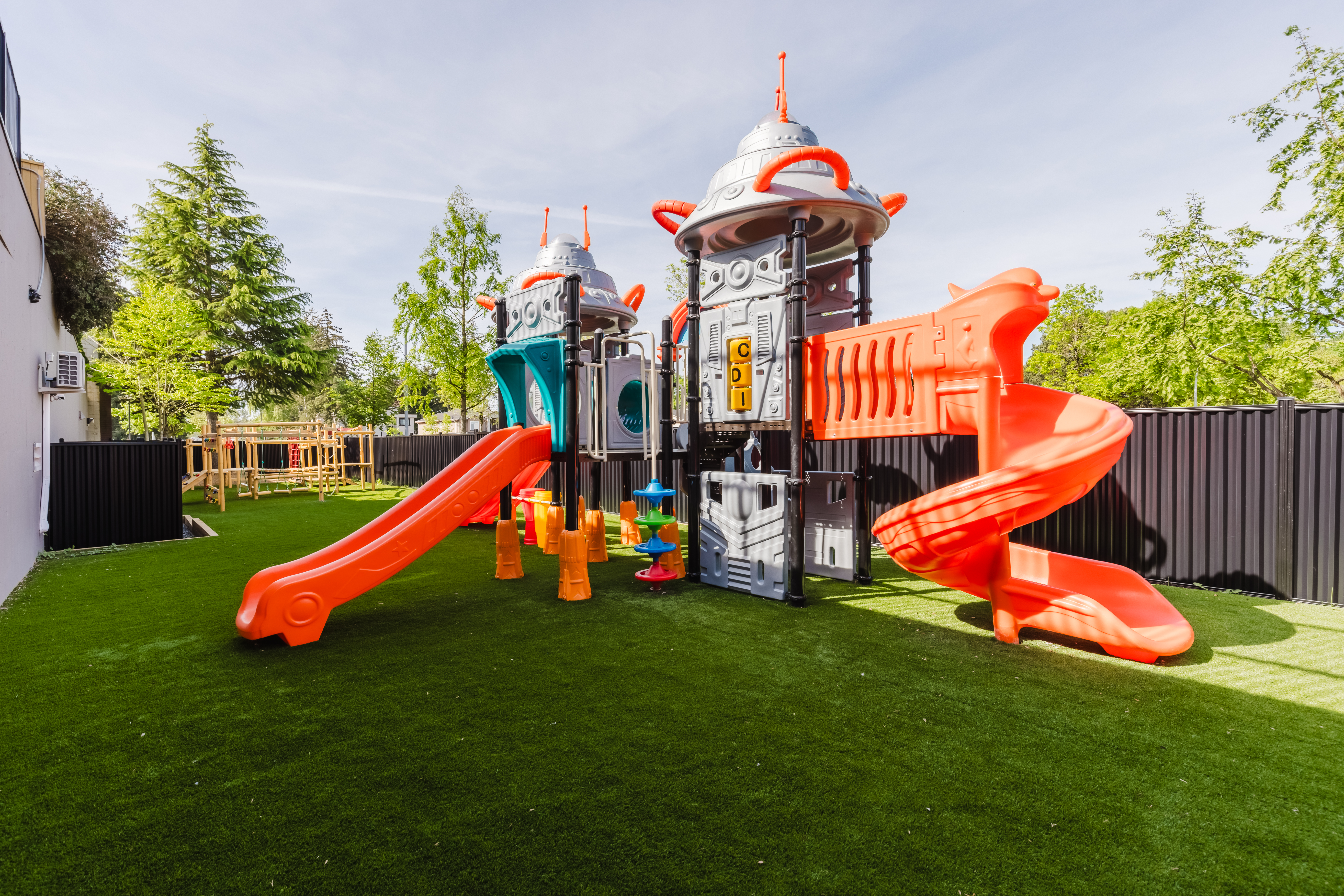Colourful outdoor play structure with orange slides and climbing panels at Kidzville
