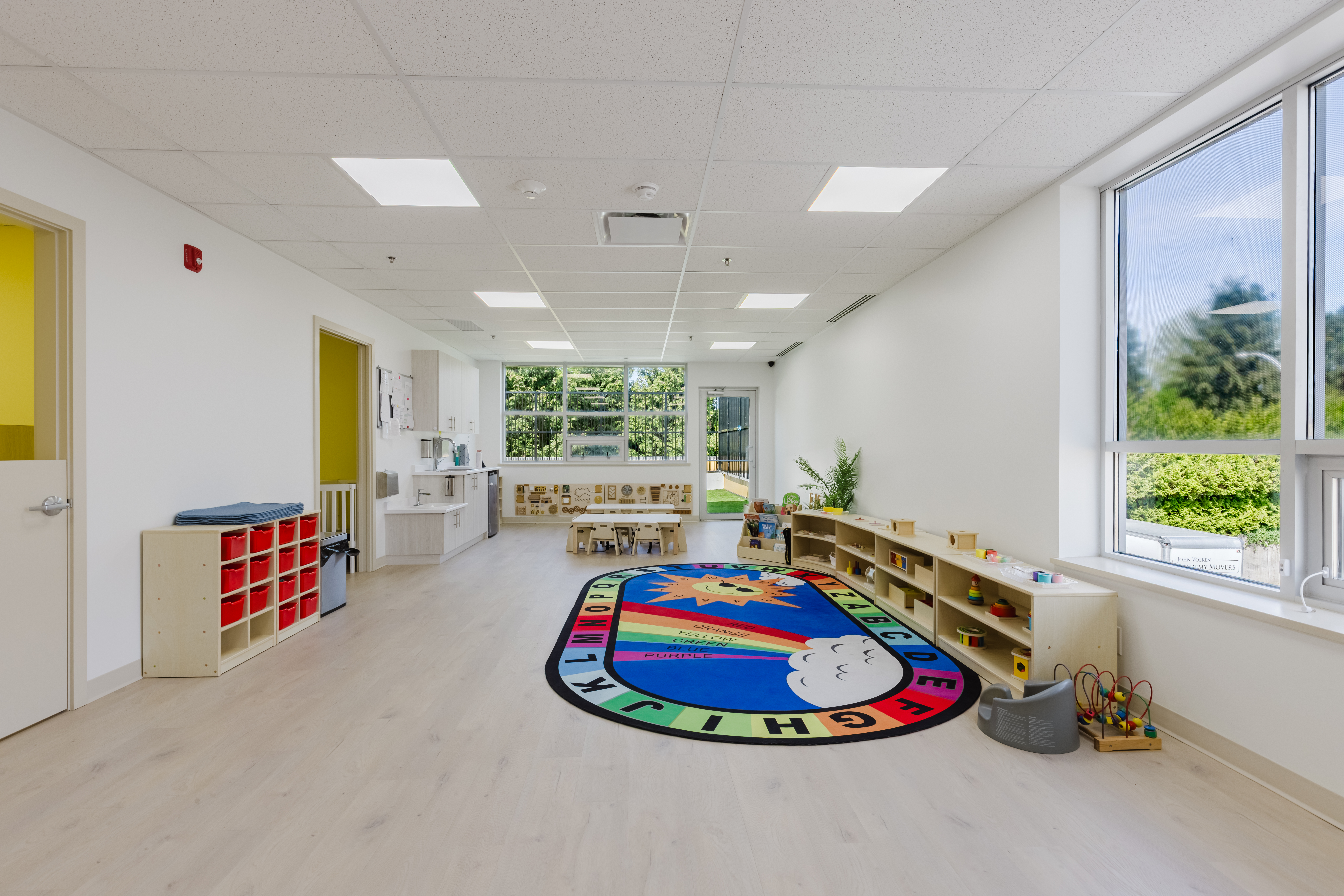 Bright infant classroom with insect rug and kitchen area at Kidzville