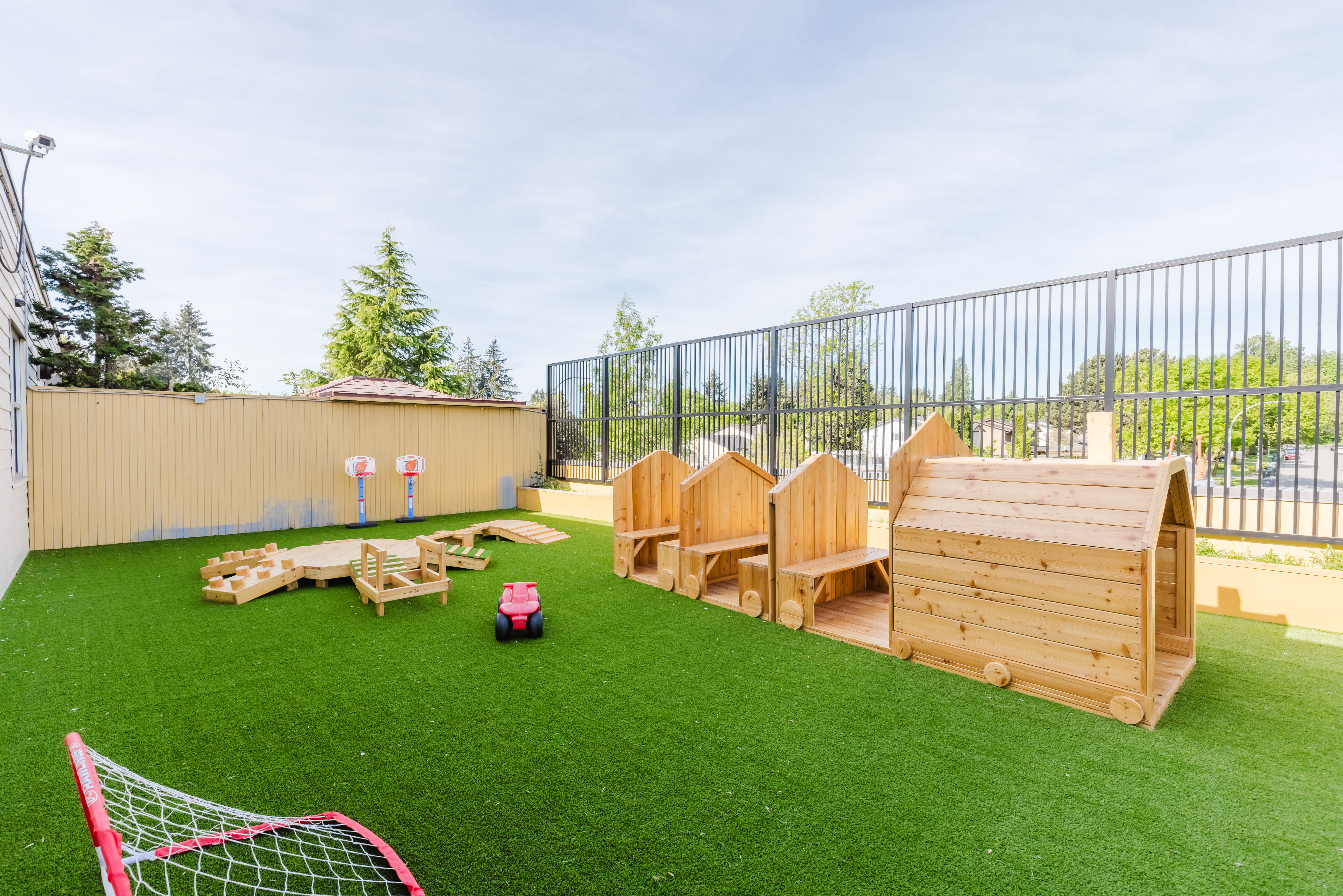 Outdoor learning area with wooden village play structures and sports equipment