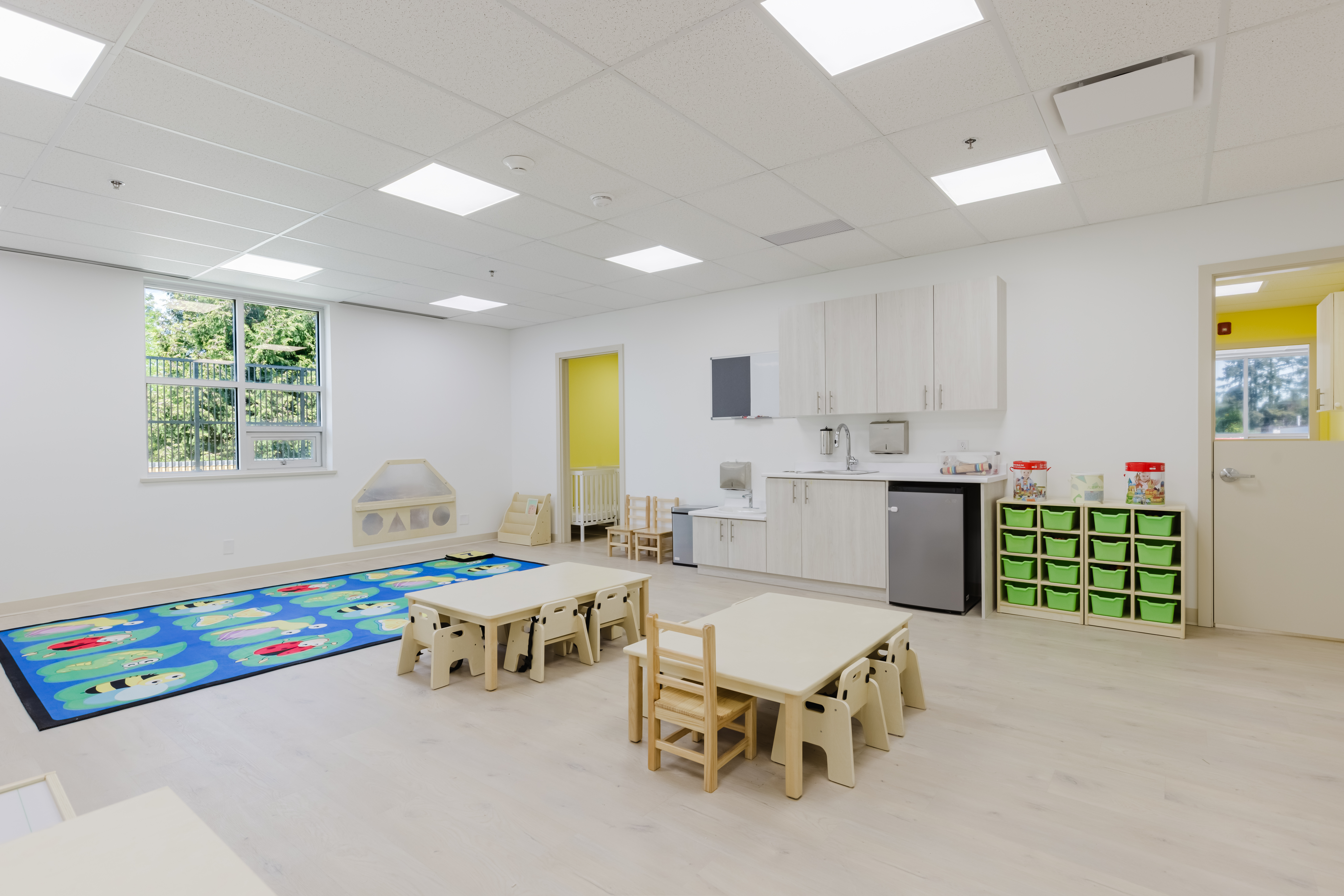 Bright, open infant classroom with alphabet rug and view of outdoors at Kidzville
