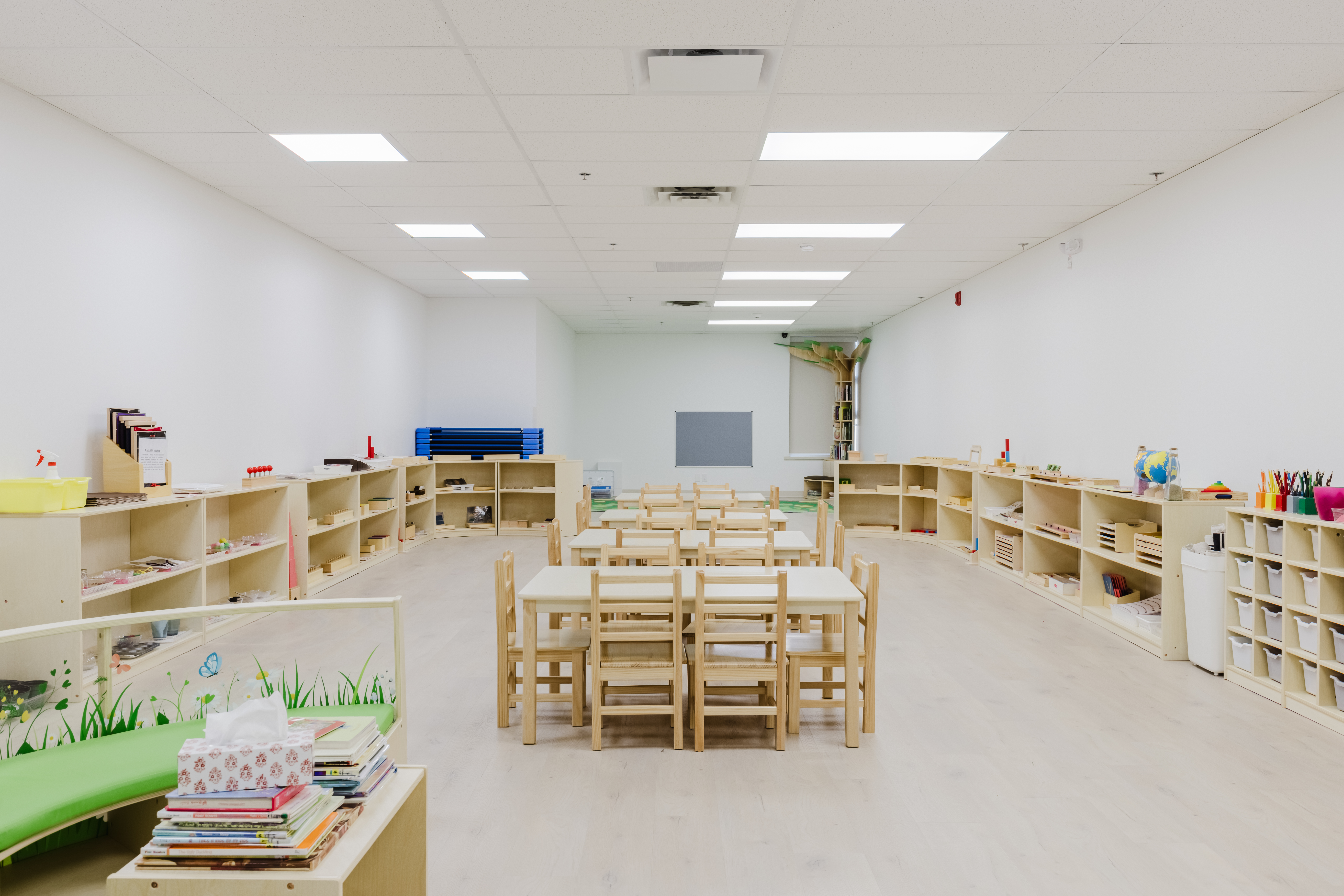 Spacious Montessori Junior Kindergarten classroom with wooden shelving and tables