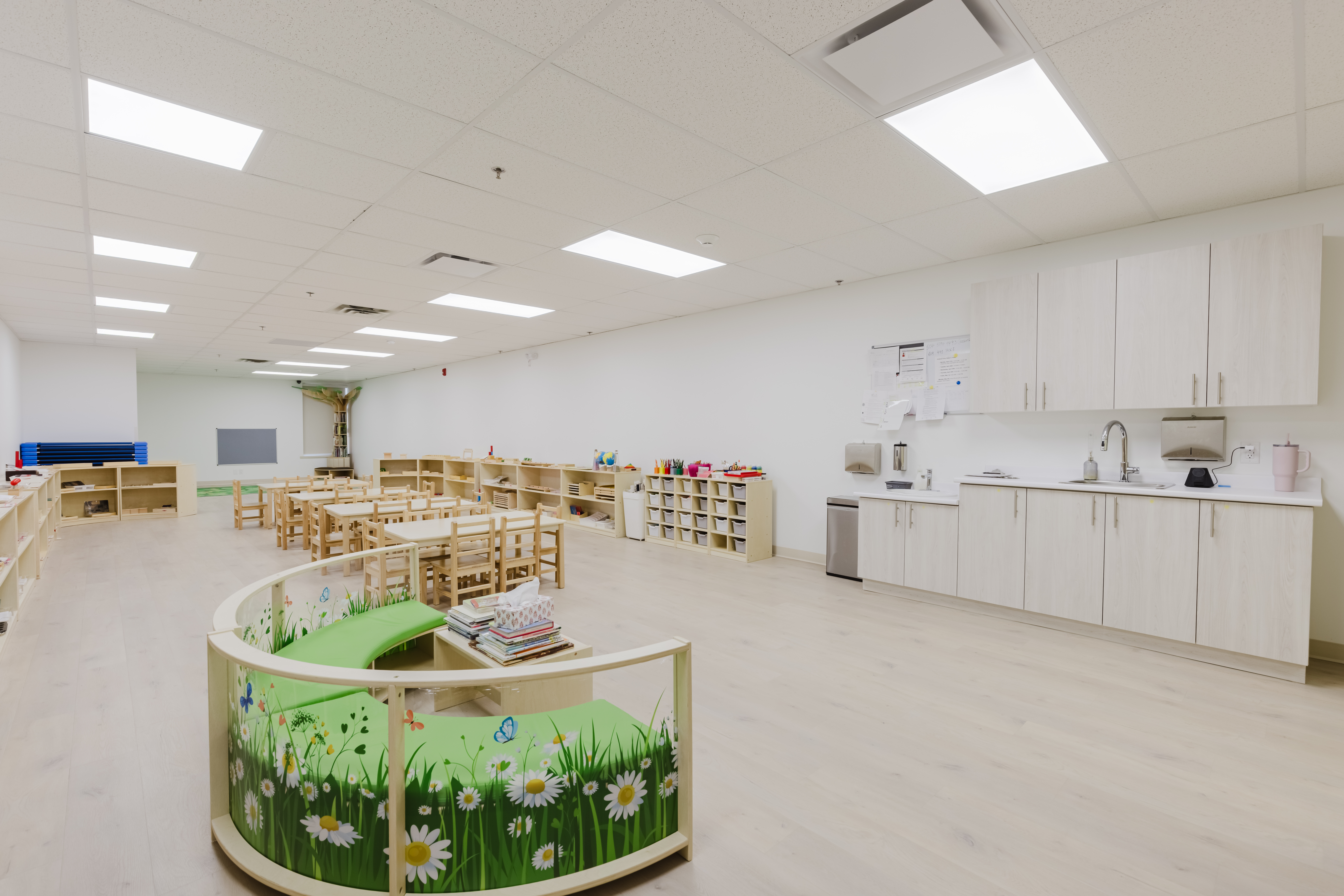 Bright, open Montessori classroom with reading nook and kitchen area at Kidzville