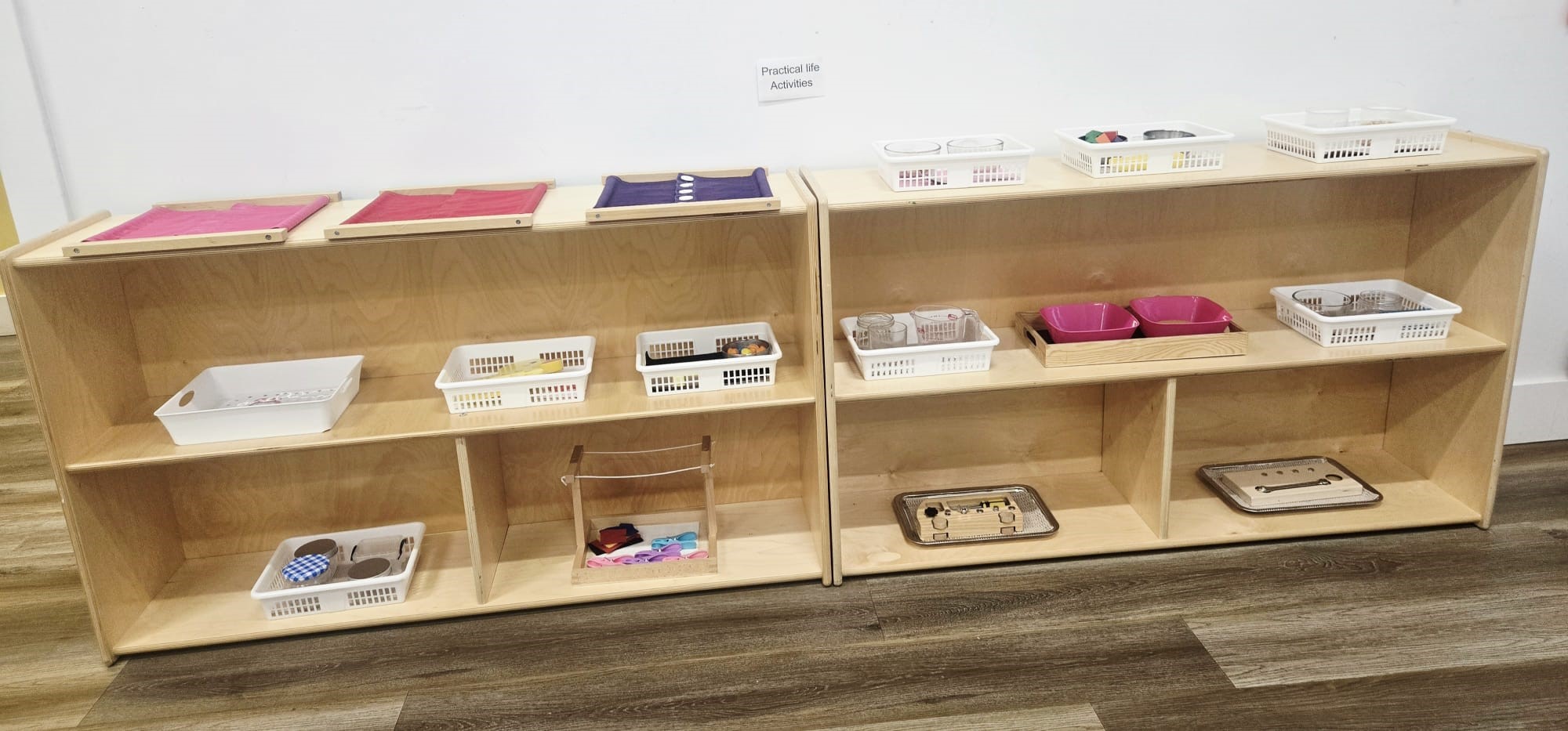 Practical life activities shelf with trays and baskets in a Kidzville classroom